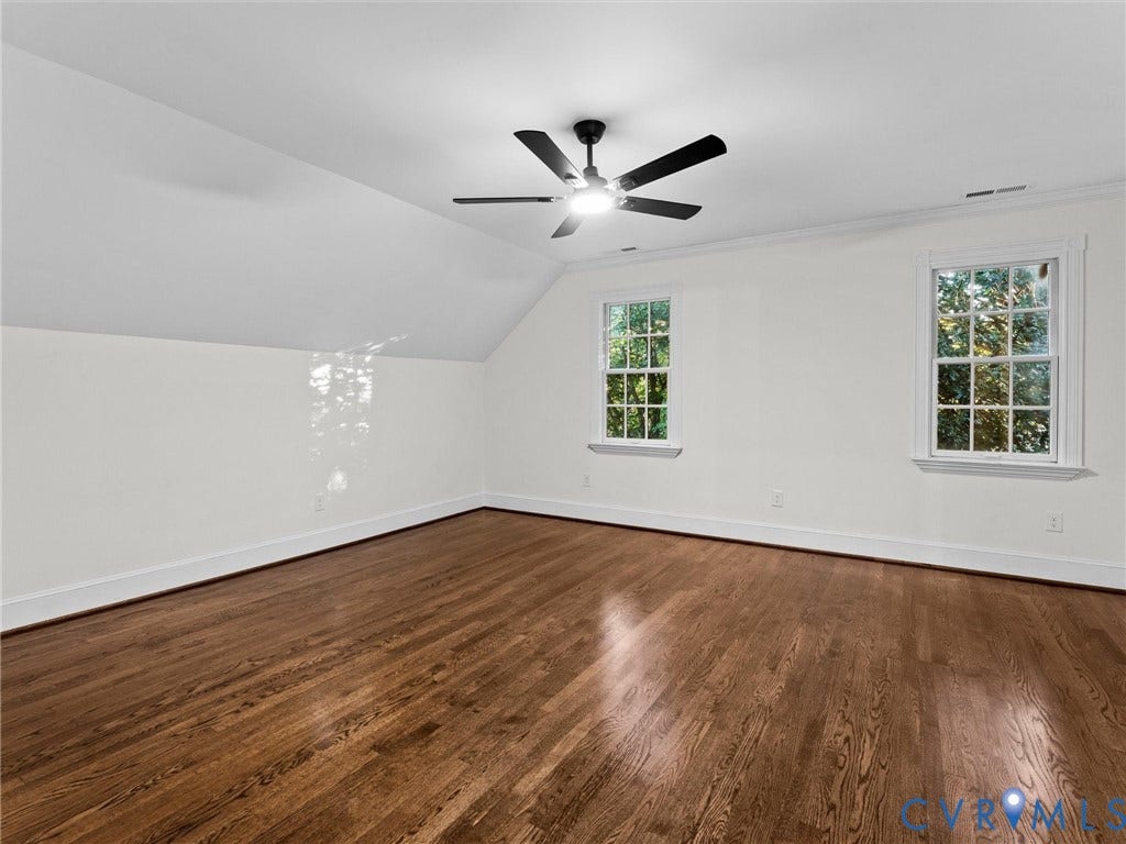 Wood-finish flooring, two multi-pane windows, crown molding, and a ceiling fan with integrated lighting