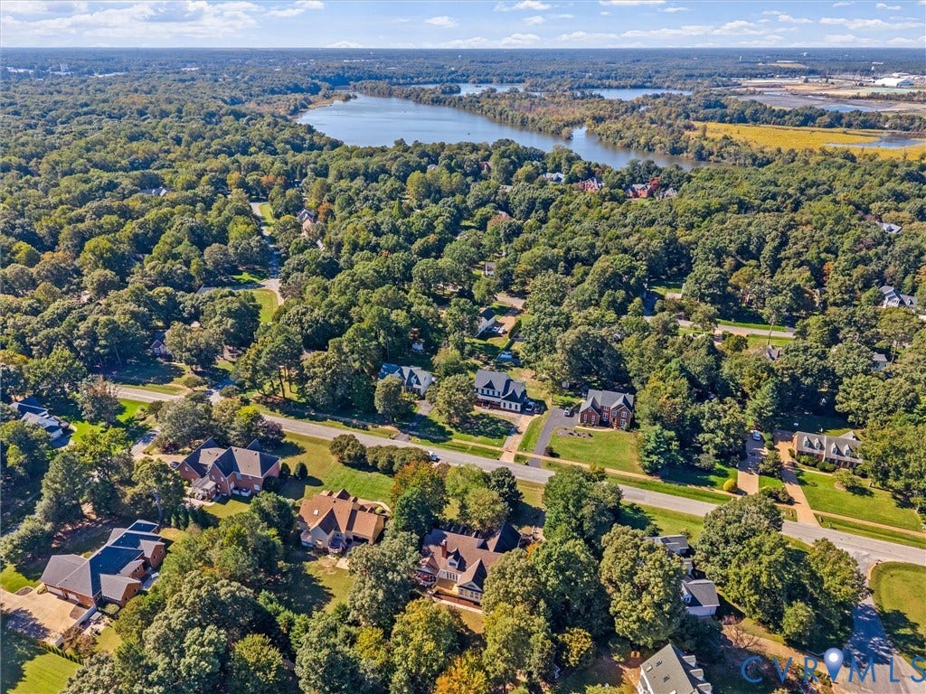 Residential properties with mature landscaping and established roadways, surrounded by extensive natural tree coverage
