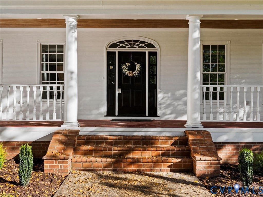 White painted brick facade with a covered porch featuring white columns and balusters