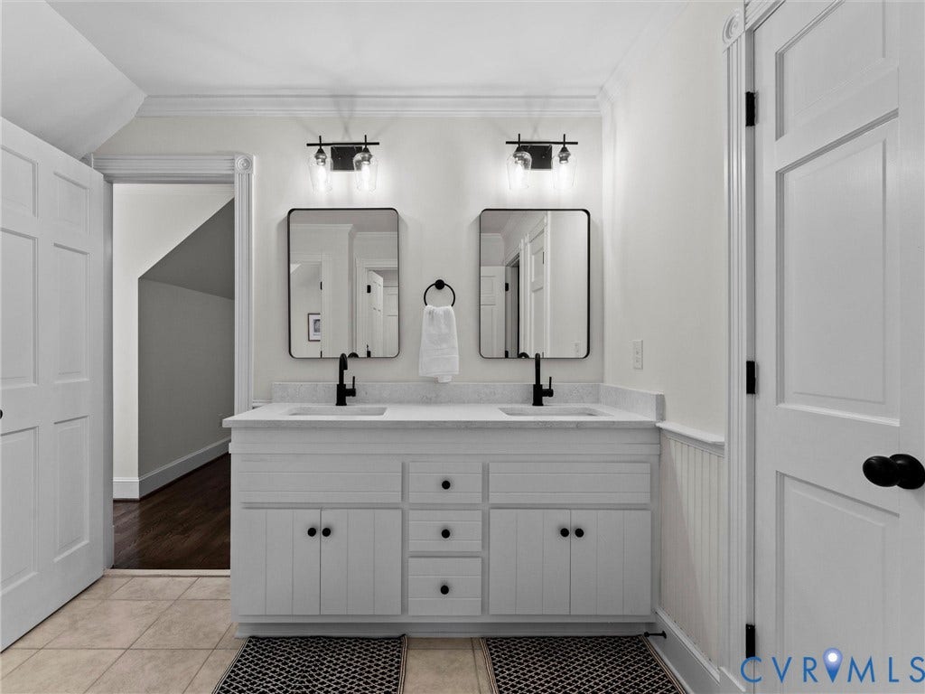 Dual vanity with white cabinetry and integrated sinks, matte black faucets, and rectangular mirrors, complemented by tile flooring