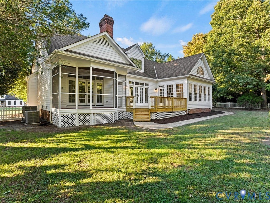 Expansive rear exterior featuring a screened porch, a wood deck, a sunroom with multiple windows, and a brick chimney