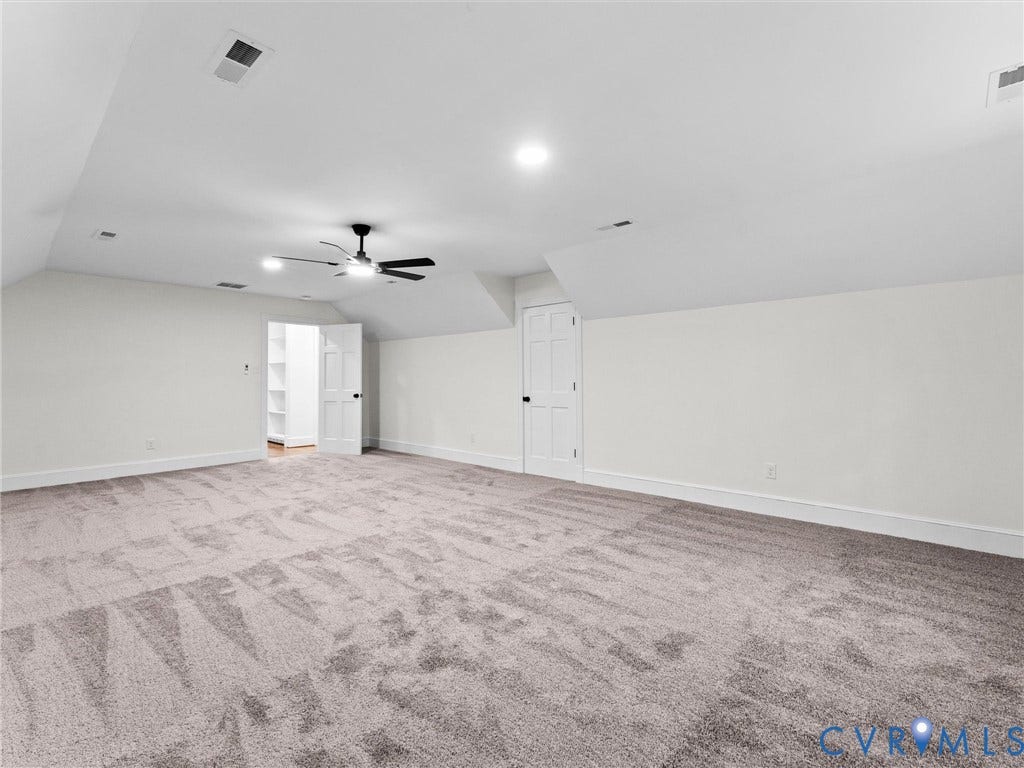 Spacious room featuring sloped ceilings, recessed lighting, a ceiling fan, and carpeted flooring