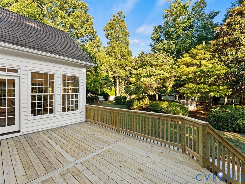 Expansive wood deck with natural wood railing, multiple windows, and a classic white exterior