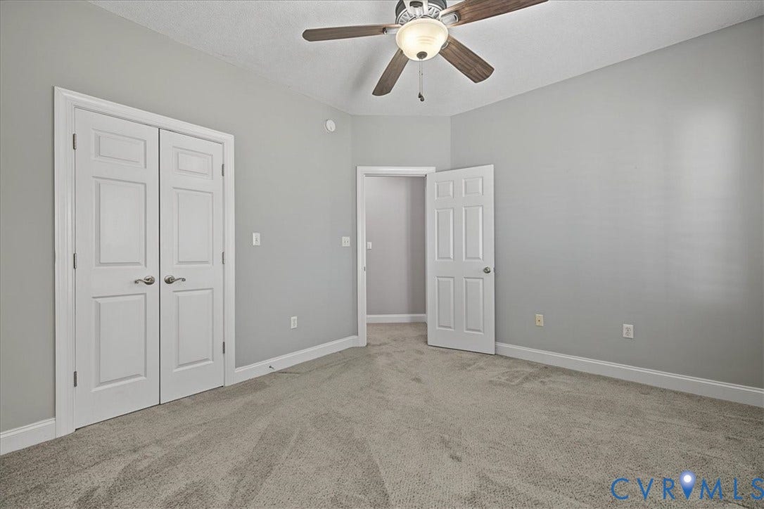 Neutral-toned bedroom featuring carpeting, ceiling fan with light fixture, six-panel doors, and double-door closet