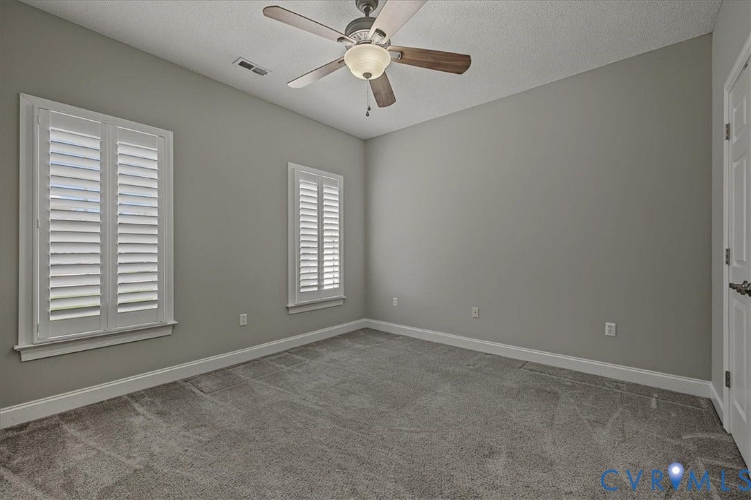 Room featuring neutral wall tones, plush wall-to-wall carpeting, plantation-style window shutters, and a ceiling fan with integrated lighting