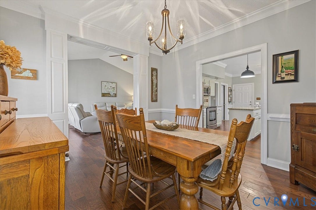 Dining area featuring wood-finish flooring, crown molding, chair rail trim, and a multi-arm metal chandelier