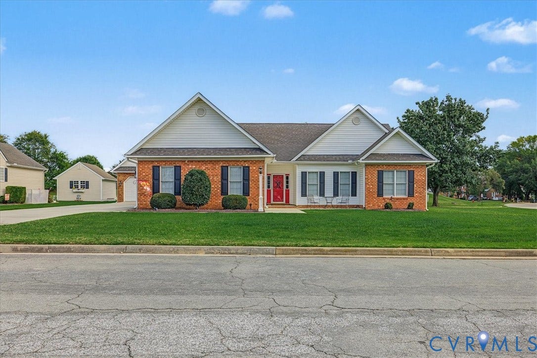 Single-story exterior featuring a brick and siding facade, contrasting dark shutters, an accented red front door, and an attached garage