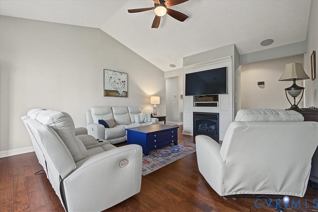 Living area with vaulted ceilings, wood-finish flooring, recessed lighting, ceiling fan, and a floor-to-ceiling built-in fireplace mantle