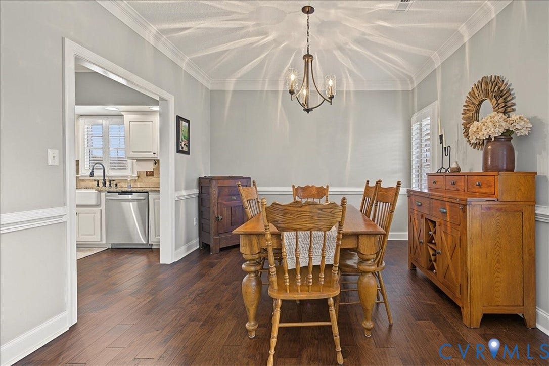 Dining area featuring dark wood-finish flooring, crown molding, chair rail trim, and a multi-arm chandelier