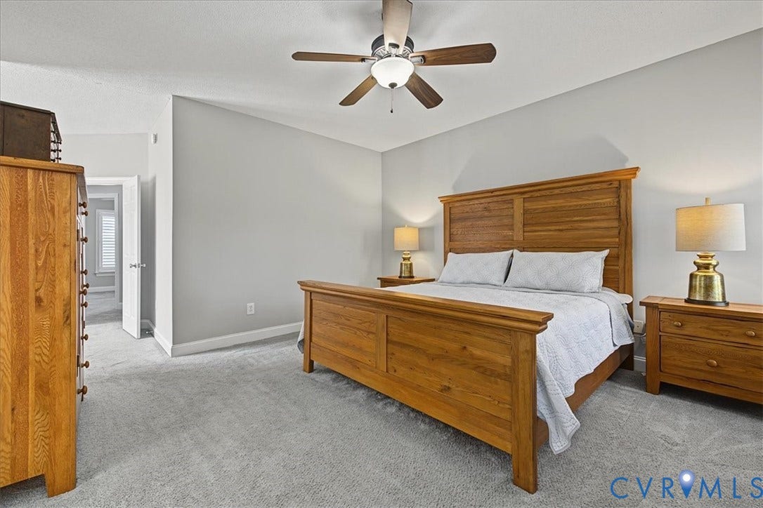 Neutral-toned wall paint, wall-to-wall carpeting, and a central ceiling fan with an integrated light fixture