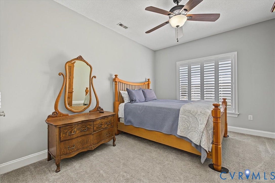 Neutral-toned interior featuring wall-to-wall carpeting, ceiling fan with integrated lighting, and plantation shutters