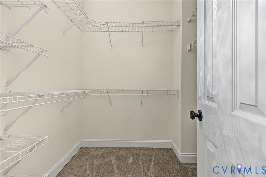 Walk-in storage space featuring multi-level wire shelving and carpeted flooring