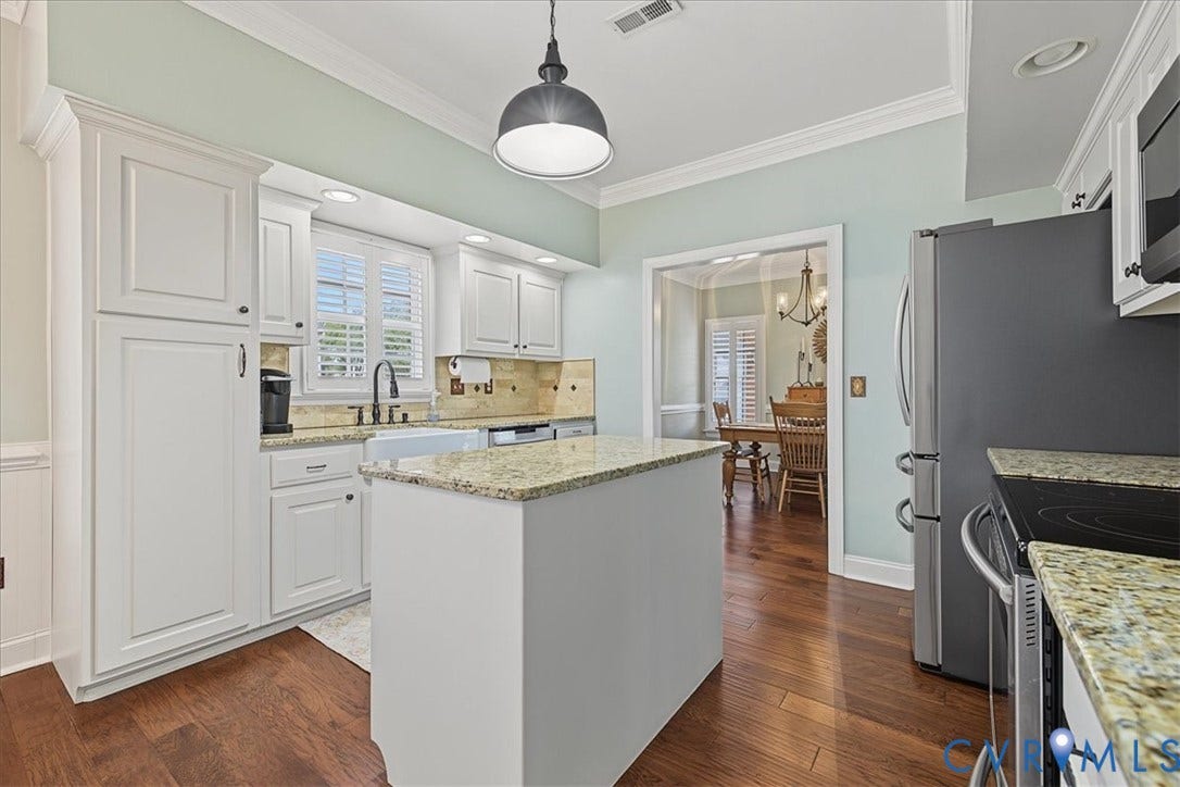 Kitchen featuring white cabinetry, stone countertops, a center island, wood-finish flooring, and a farmhouse-style sink