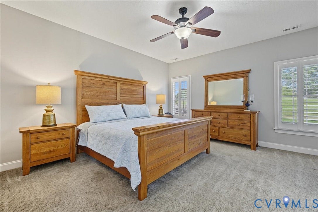 Neutral wall tones, wall-to-wall carpeting, ceiling fan with integrated lighting, and white plantation shutters