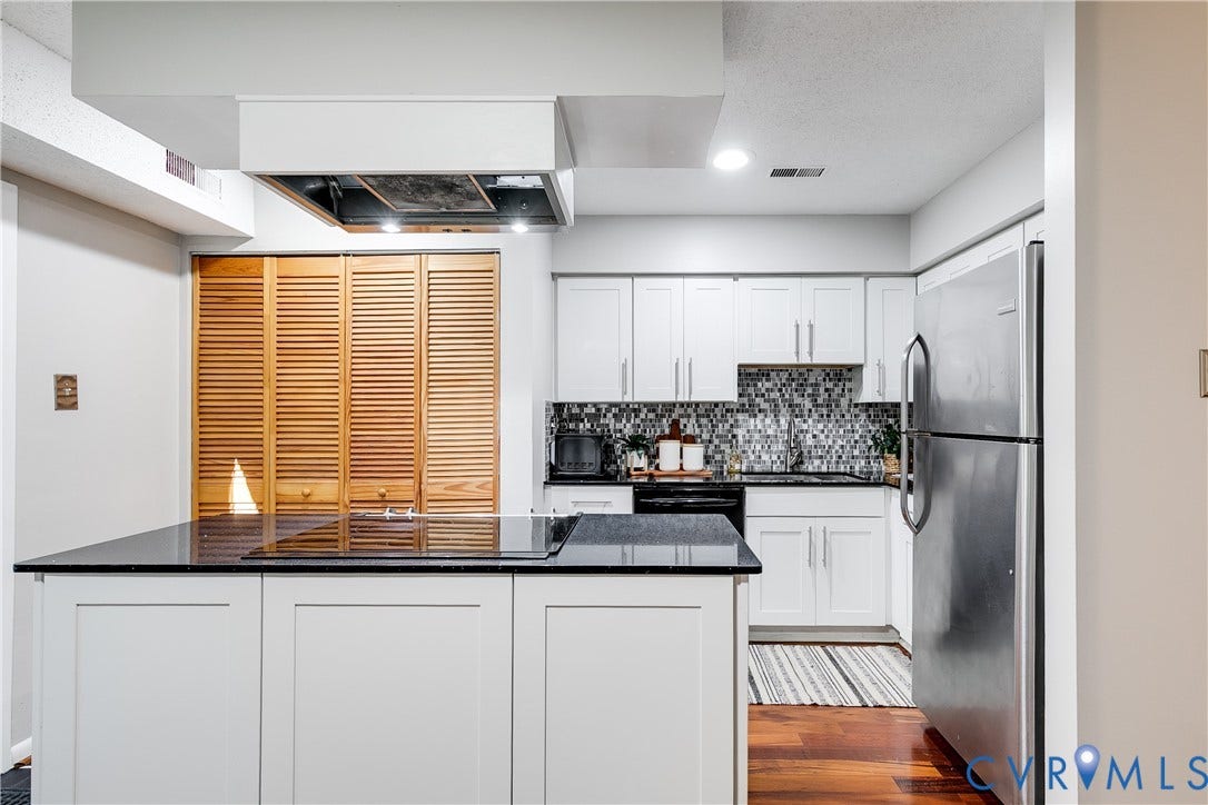 Granite island with stove and lots of cabinets.