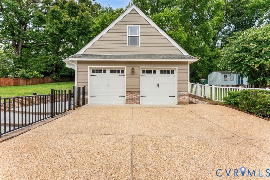 606 Westham Woods Drive, Tuckahoe, Henrico, VA 23229 Two-car garage with carriage-style doors, exposed aggregate driveway, and siding exterior with brick accents