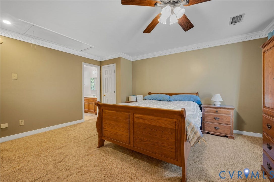 Carpeted room with crown molding, a ceiling fan with integrated lighting, and direct access to a bathroom featuring a wood-finish vanity