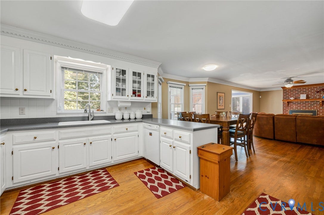 White cabinetry with gold-tone hardware, a white tile backsplash, and a double basin sink