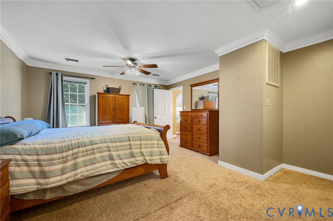 Crown molding, ceiling fan, natural light from a window, carpeted flooring, and neutral wall tones