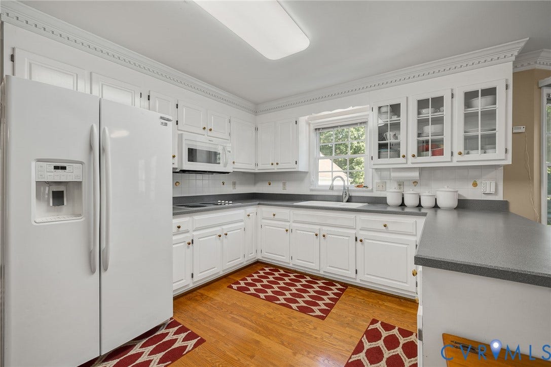 Kitchen featuring white cabinetry, gray countertops, a built-in microwave, wood-finish flooring, and crown molding