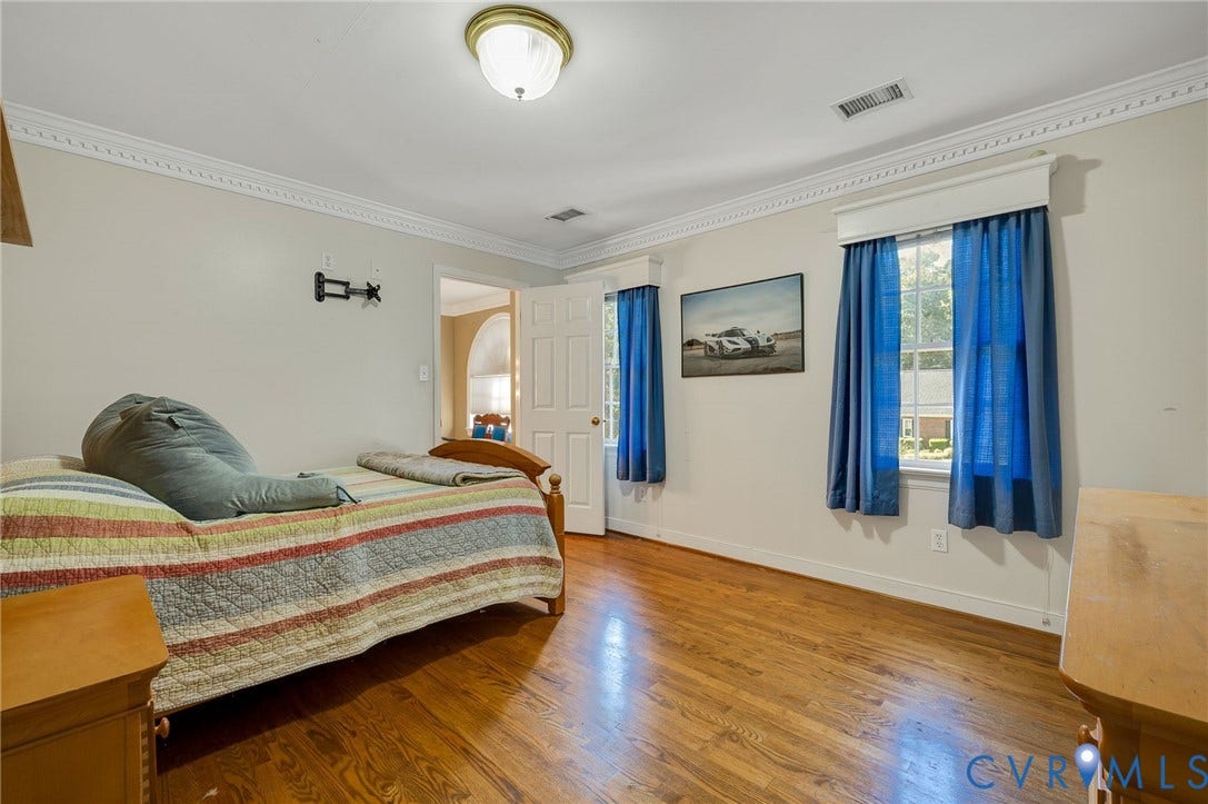 Hardwood flooring, crown molding, double windows, ceiling-mounted light fixture, and a paneled door