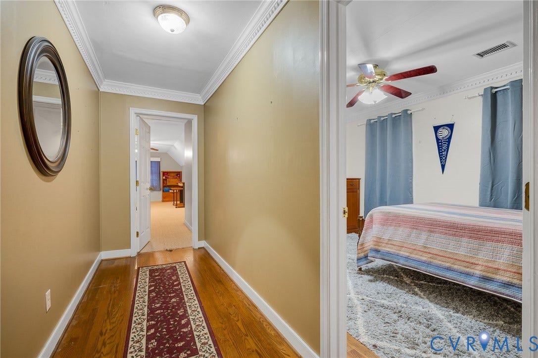 Hardwood flooring, decorative crown molding, and ceiling light fixture