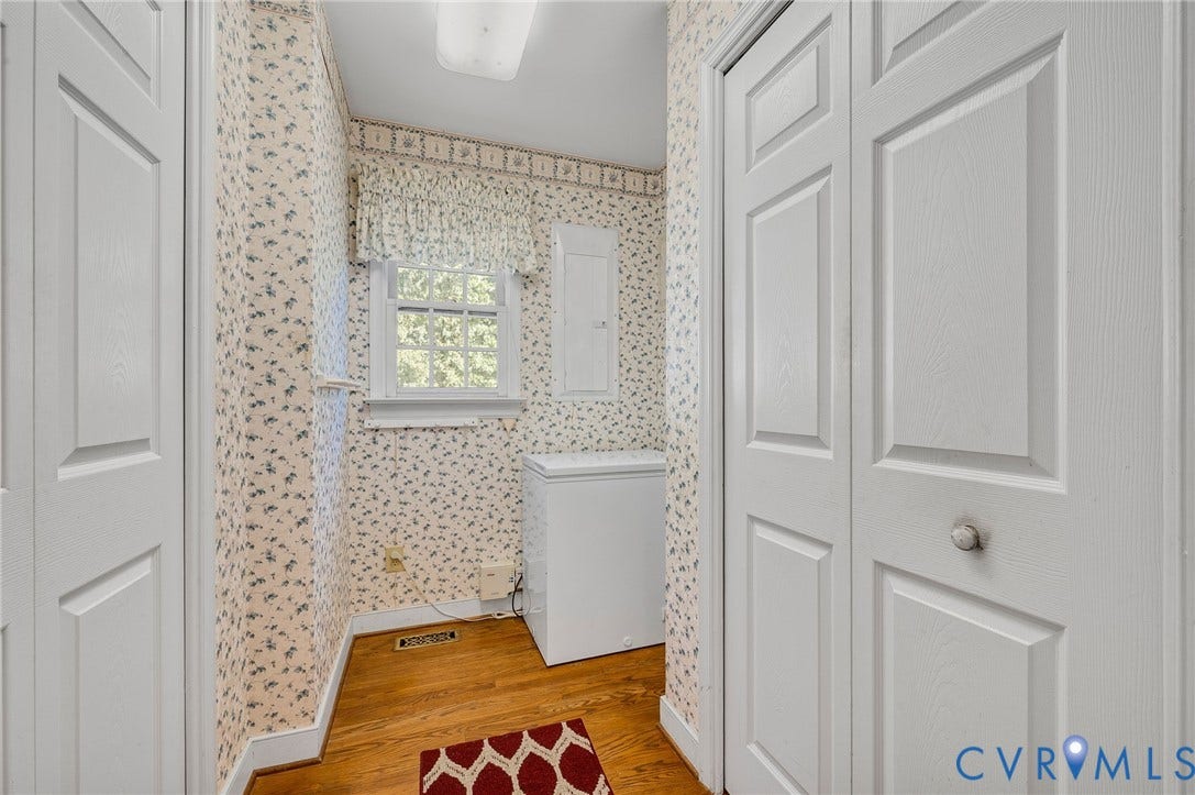 Wood-finish flooring with white trim and a white paneled window