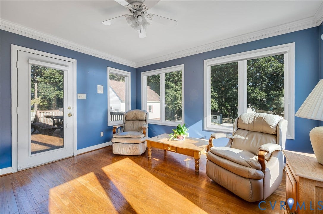 Wood-finish flooring, ceiling fan, white crown molding, multiple windows, and a glass-paneled exterior door