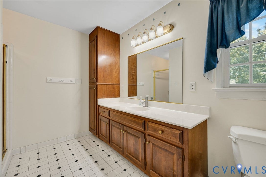 Vanity with wood-finish cabinetry, white countertop, and integrated sink