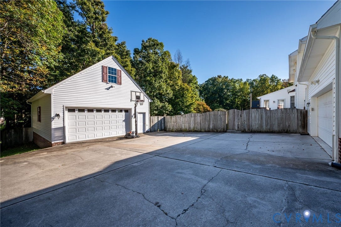 Detached two-car garage with white paneled door, vinyl siding, and attic window