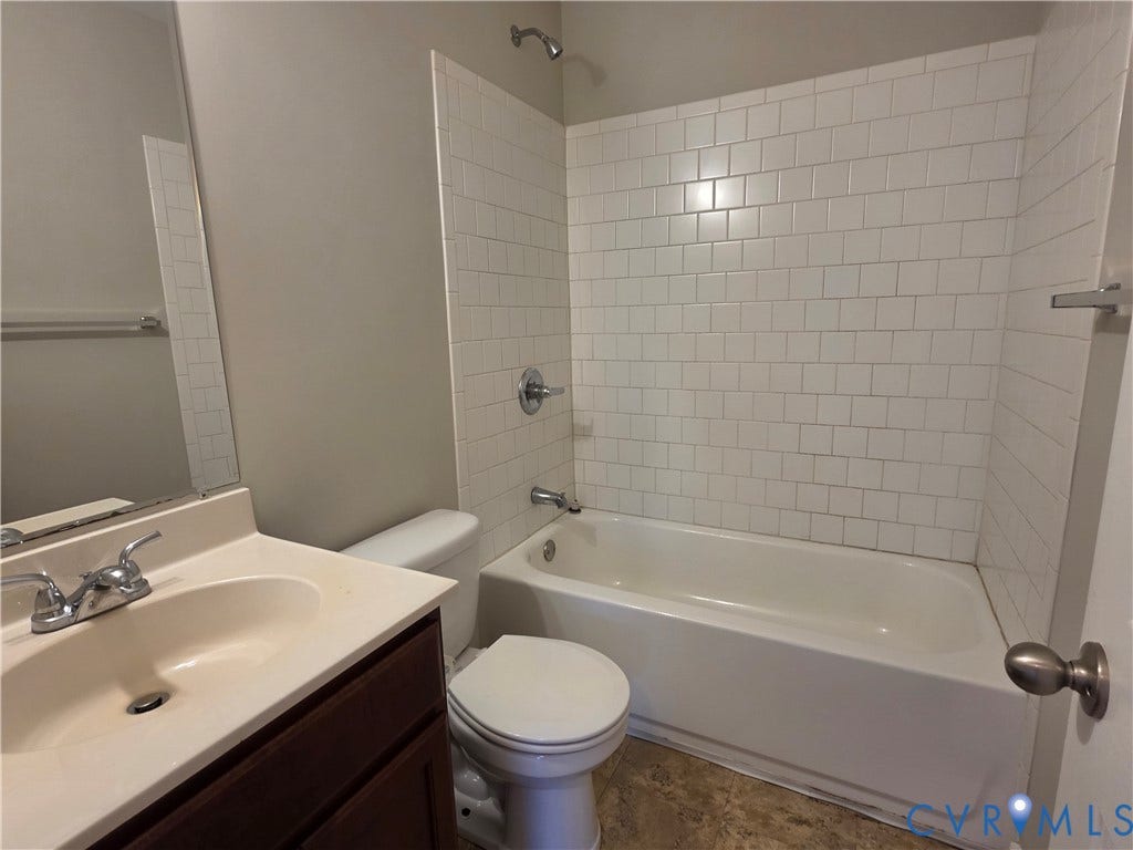 Bathroom featuring a white subway tile tub surround, white bathtub, chrome fixtures, dark wood-finish vanity, and a large mirror