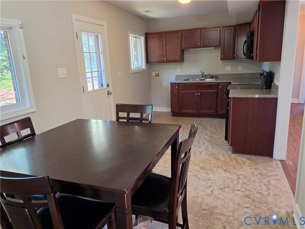 Kitchen featuring dark wood cabinetry, light-colored countertops, black appliances, and a light-toned patterned floor