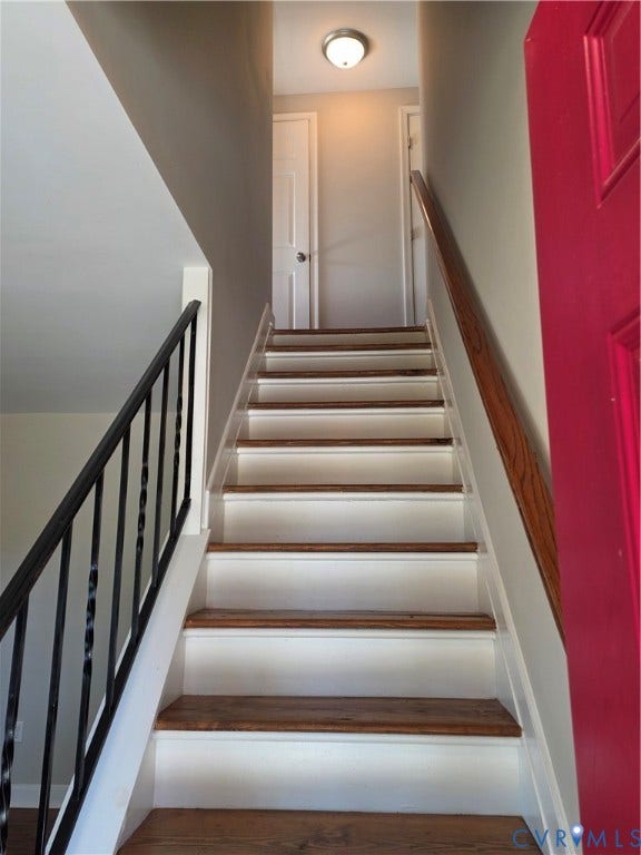 Staircase featuring wood-finish treads, white risers, and a black wrought-iron handrail