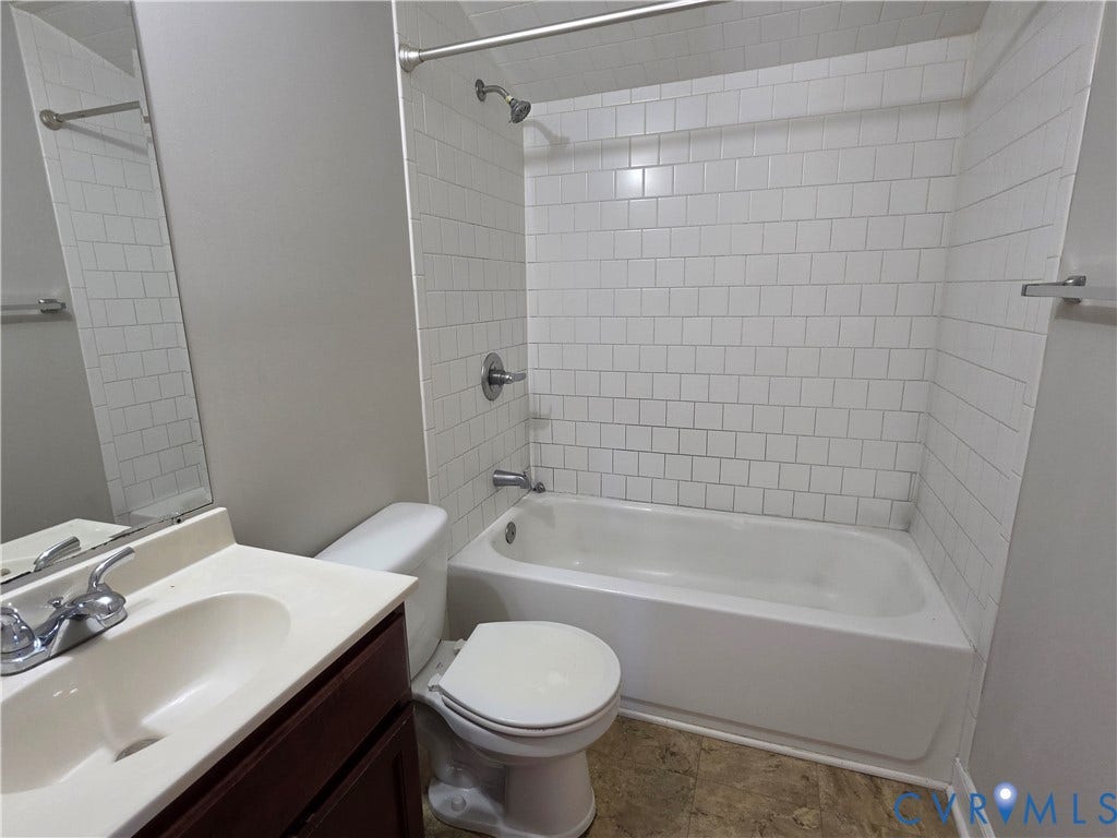 Bathroom featuring a shower/tub combination with white subway tile surround, chrome fixtures, and a vanity with an integrated sink