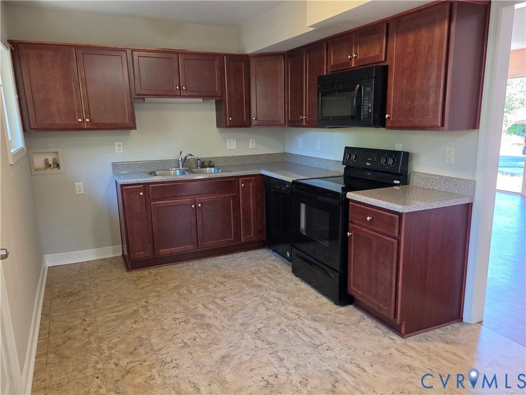 Kitchen featuring wood-finish cabinetry, speckled countertops, stainless steel double basin sink, and wood-finish flooring