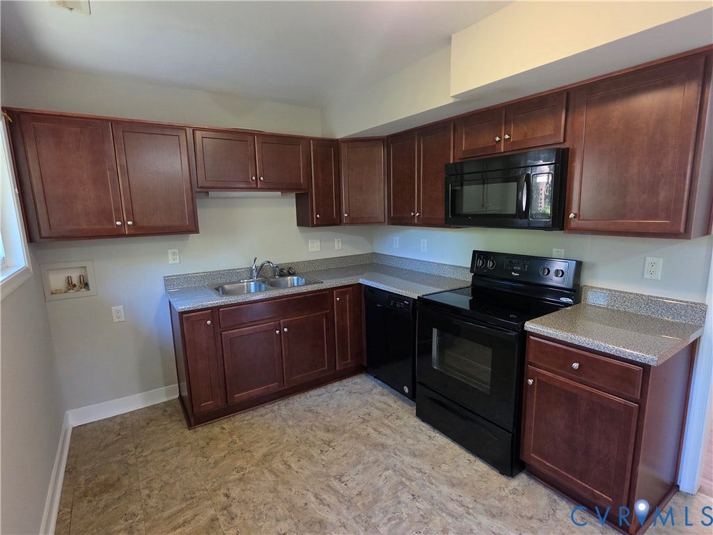 Kitchen featuring wood-finish cabinetry, granite-style countertops, double basin sink, and black appliances