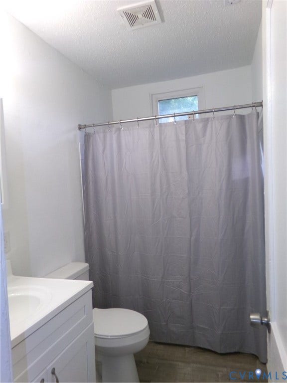 Vanity with integrated sink, wood-finish flooring, toilet, and window with natural light