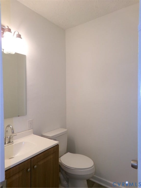Vanity with wood-finish cabinetry, white countertop, and integrated sink