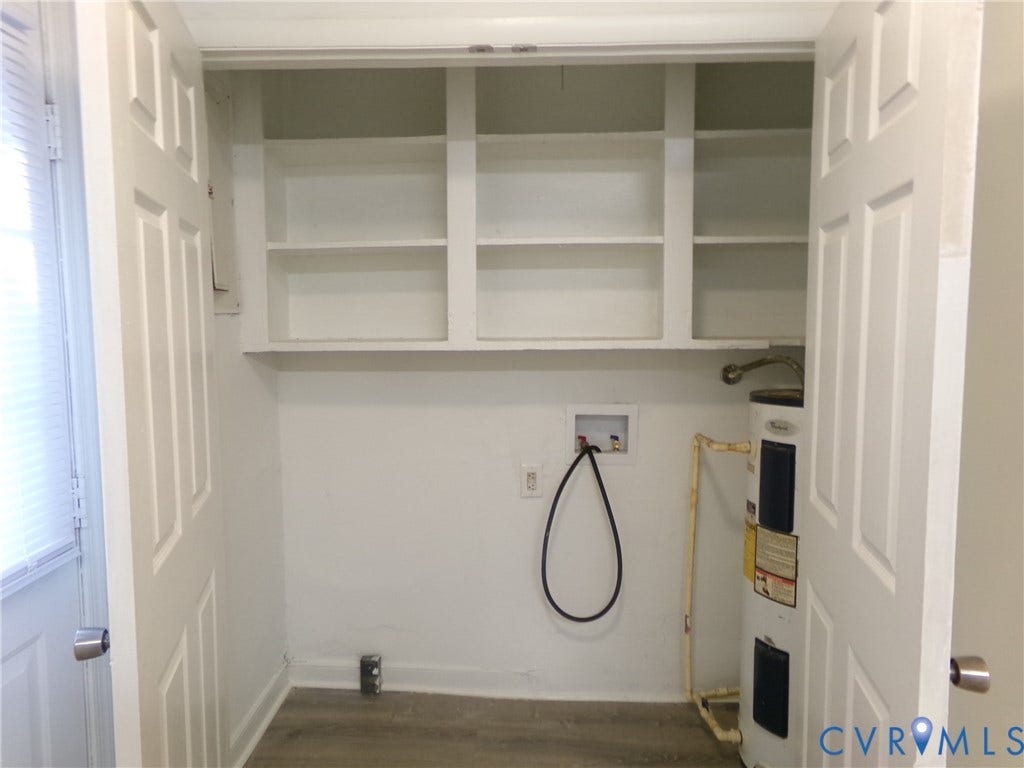 Utility area with built-in shelving, water heater, and wood-finish flooring