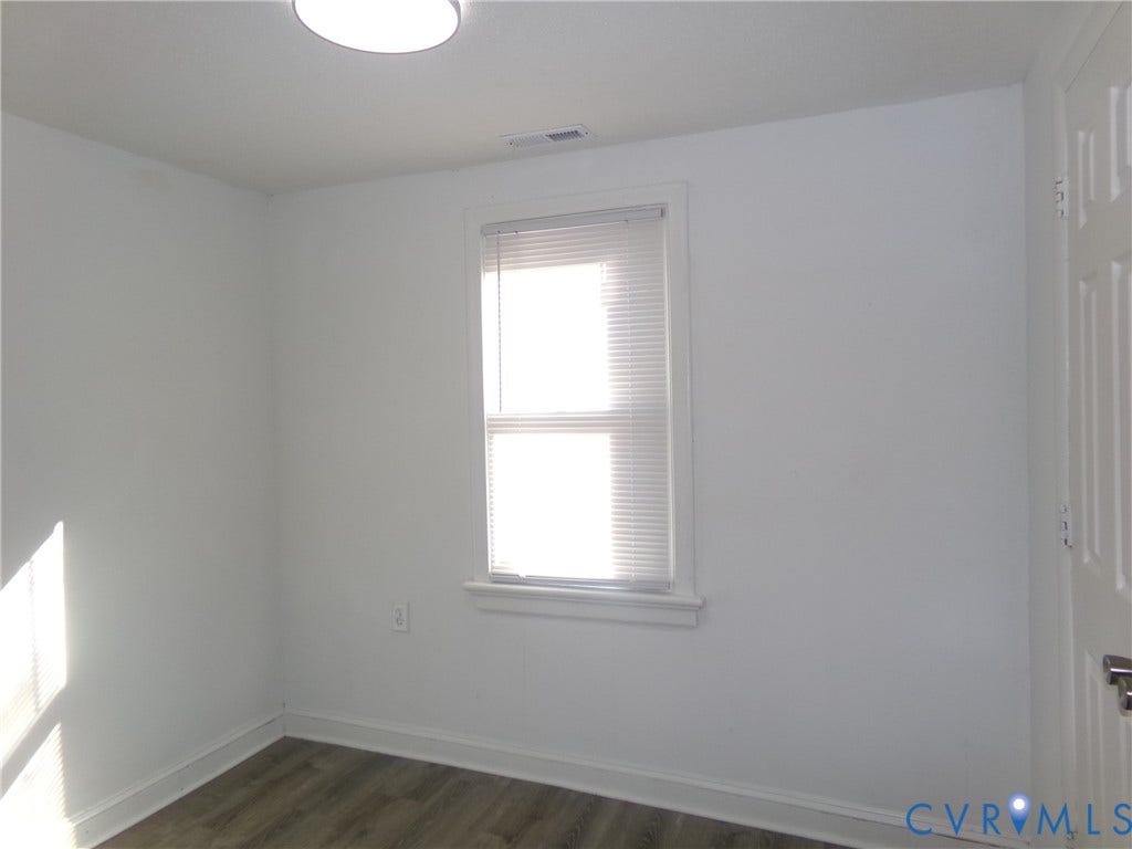 Recessed lighting fixture, window with blinds, wood-finish flooring, and a paneled door