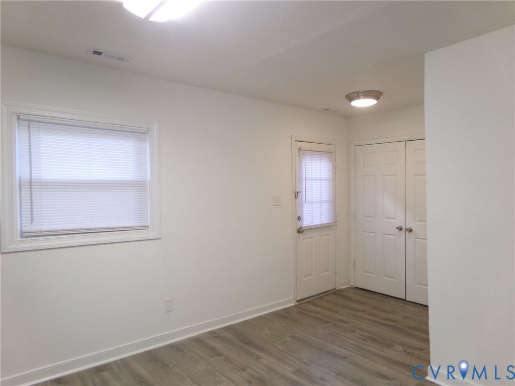 Wood-finish flooring, white walls, and a window with blinds
