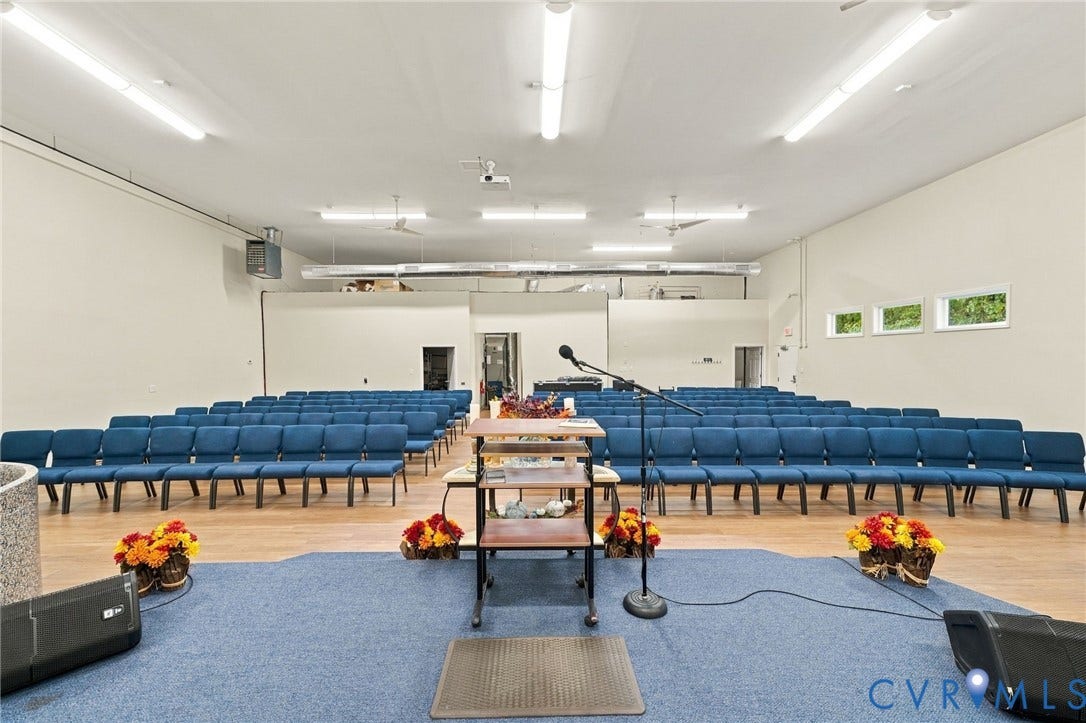 Spacious open-concept interior featuring wood-finish flooring, fluorescent lighting, and multiple windows