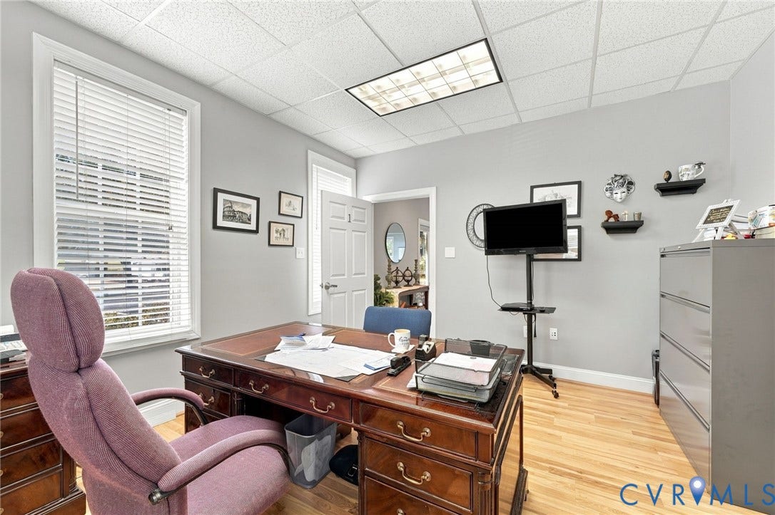 Hardwood-finish flooring, drop ceiling with integrated lighting, window with blinds, and painted walls