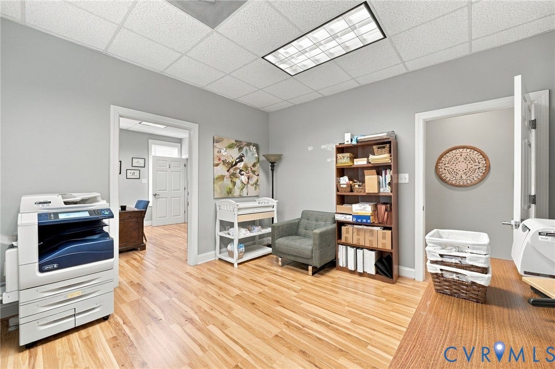 Hardwood flooring throughout, suspended ceiling with integrated lighting, and light grey wall finishes