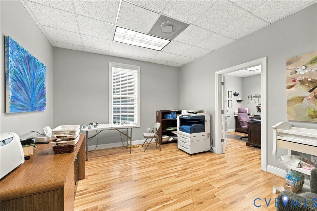 Light-toned wood-finish flooring, neutral gray wall paint, white trim, recessed lighting, and a drop ceiling