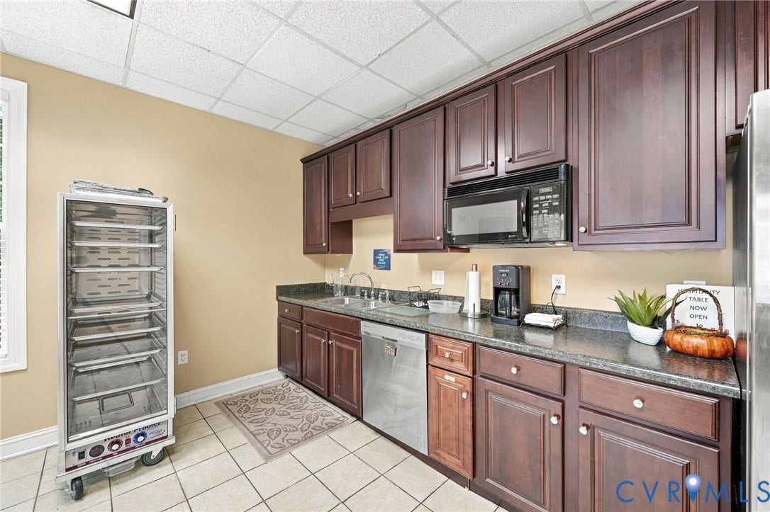 Dark wood-finish cabinetry with silver hardware, black countertops, and stainless steel appliances