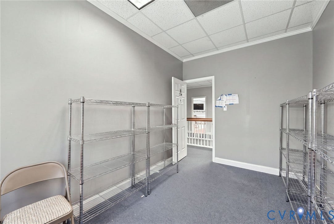 Neutral gray wall paint, drop ceiling, white trim, gray flooring, open doorway