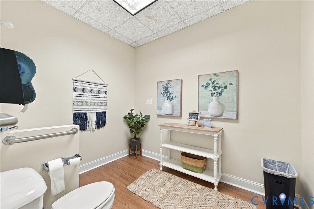 Wood-finish flooring with white baseboards, recessed lighting, and a drop ceiling
