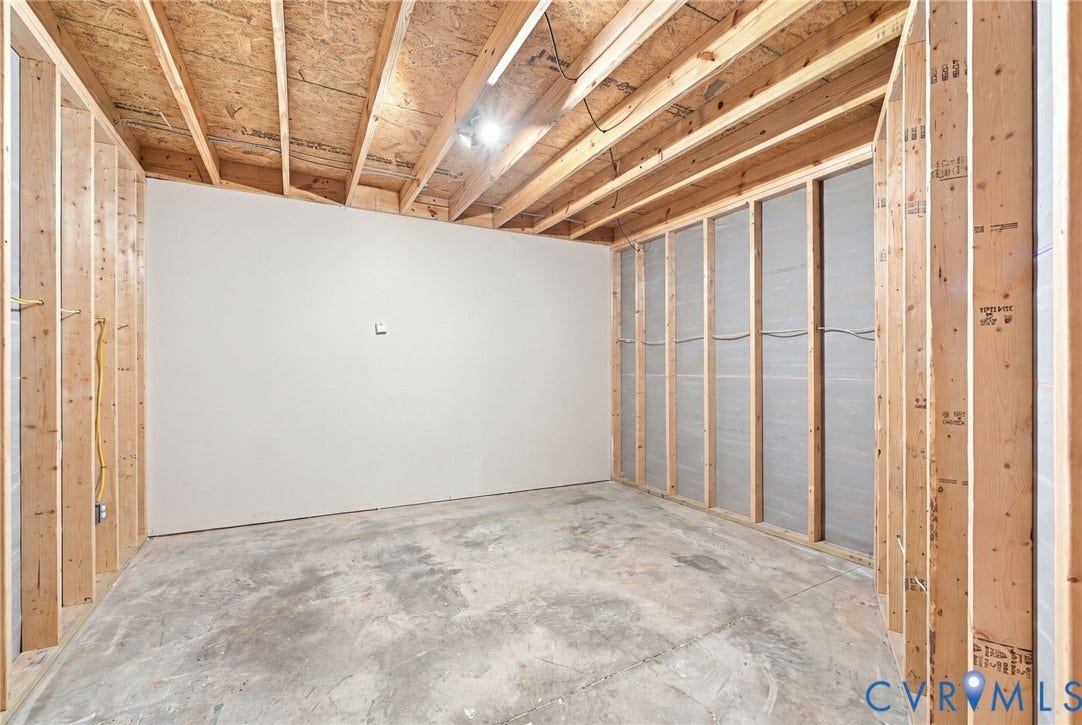 Unfinished interior space with exposed ceiling joists, wood framing, and a concrete floor