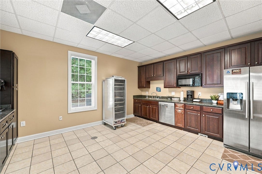Spacious kitchen featuring extensive dark wood cabinetry, stainless steel appliances, granite-style countertops, and tiled flooring